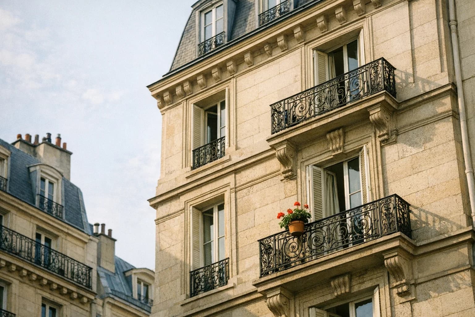 Facade en pierre d'un immeuble haussmannien avec balcons en fer forge, lumiere matinale